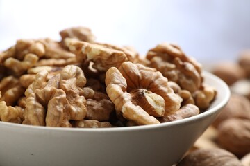 Peeled walnuts in bowl on table against light background, closeup