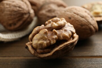 Fresh walnuts with shells on wooden table, closeup