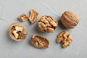 Fresh walnuts with shells on gray textured table, flat lay
