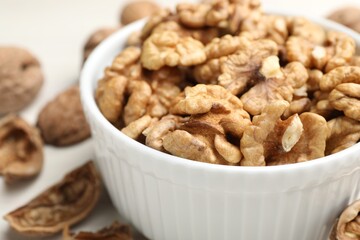 Peeled walnuts in bowl on light table, closeup