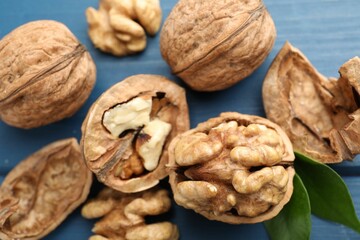 Fresh walnuts with shells on blue table, flat lay