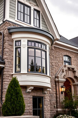 Naklejka premium Elegant Stone House Exterior with Bay Window and Classic Design. Luxurious Home Architecture, Real Estate, and Property Photography