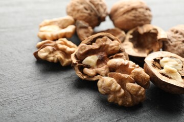Fresh ripe walnuts and shells on black table, closeup. Space for text