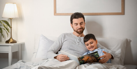 Father reading bedtime story to his little son in bedroom