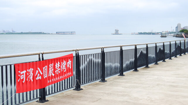 Tamsui, Taiwan - 21 October 2023: Tamsui Golden Anchor Park has a strolling path and a mountain-shaped fence. Barbecuing is prohibited in Riverside Park (Translation from Chinese text on the red flag) - Powered by Adobe