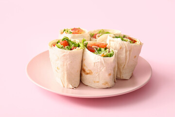 Plate of tasty lavash rolls with tomatoes and greens on pink background