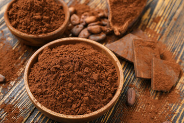 Bowls with cocoa powder on wooden background