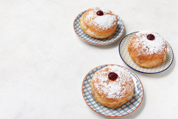 Plates with tasty donuts for Hanukkah celebration on light background