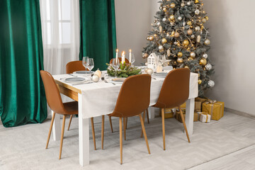 Festive table setting with burning candles and Christmas decorations in elegant dining room