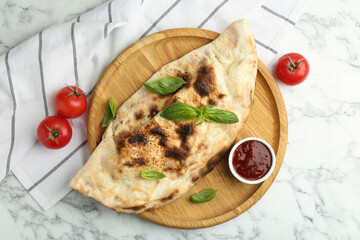 Delicious calzone served on white marble table, top view