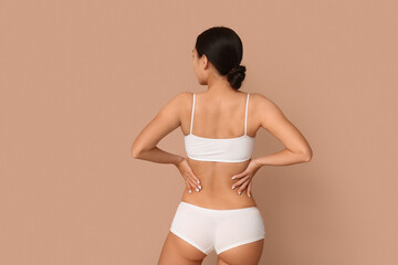 Slim young woman in underwear on beige background, back view. Weight loss concept