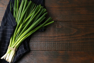 Bunch of fresh green onions on wooden table, top view. Space for text