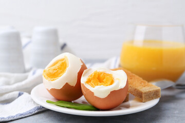 Soft boiled eggs with bread on grey table, closeup