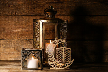 Muslim lamps with burning candles and decorative crescent for Ramadan on dark wooden background