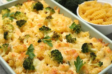 Tasty pasta casserole with cheese and broccoli in baking dish on table, closeup