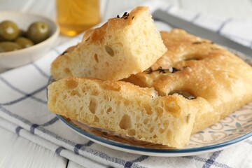 Slices of delicious focaccia bread with olives, thyme and salt on table, closeup