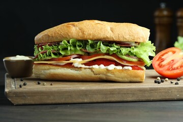 Delicious baguette sandwich with salami and cheese on grey wooden table