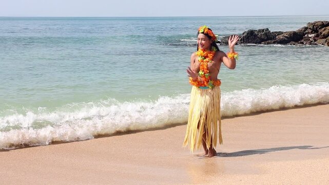 Hula Hawaii dancer dancing on the beach and pointing to the tropical sea with an invitation gesture