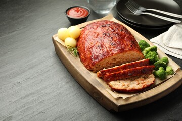 Delicious turkey meatloaf with vegetables served on black table, closeup. Space for text