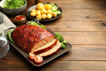 Delicious turkey meatloaf with vegetables on wooden table. Space for text