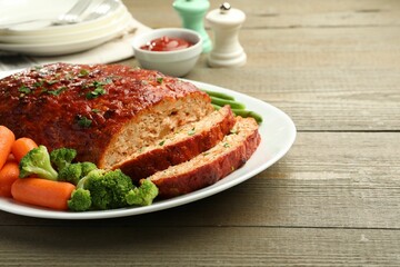 Delicious baked turkey meatloaf with vegetables served on wooden table, closeup. Space for text