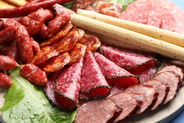 Different smoked sausages and other snacks on board, closeup