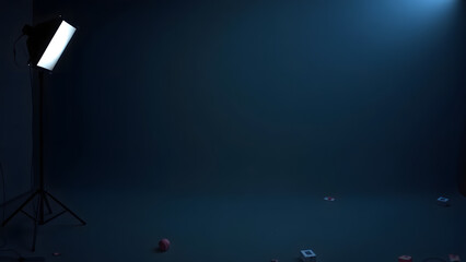 dark studio with a single spotlight illuminating the background. The space is empty except for a few colorful objects on the ground.