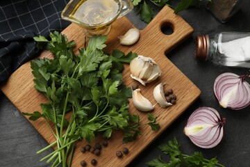 Fresh parsley and spices on black table, flat lay