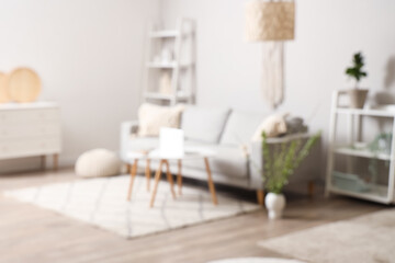 Stylish living room with sofa, coffee table and blooming branches, blurred view