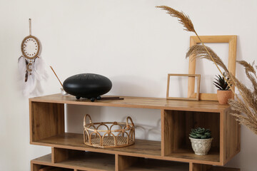 Glucophone with aroma sticks on shelf near light wall in room