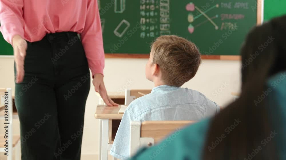 Poster energetic smart teacher explain classwork to caucasian boy at classroom while multicultural student 