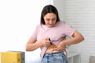 Diabetic young woman using lancet pen in office