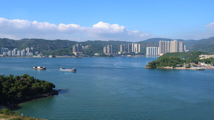 Fototapeta premium Lantau Island, Hong Kong - 5 November 2023: Ma Wan Village and Ng Kwu Leng viewed from Kap Shui Mun Bridge, with Tsing Lung Tau city in the background.