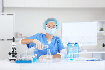 Female young scientist with professional glassware examining water quality in research laboratory