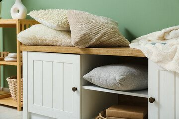 Soft cushions on cabinet near green wall, closeup