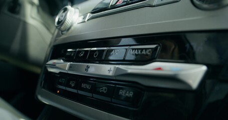 Obraz premium A woman's hand presses a button on the car's audio player while driving, close-up, unrecognizable person