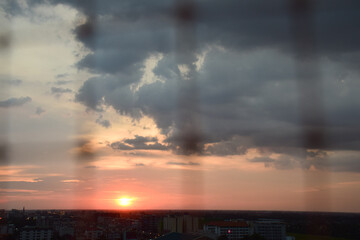 Nakhon Pathom, Thailand - April 30, 2015: Cityscape View Through Bird Protection Net in Morning Light with Urban Skyline and Cloudy Golden Sky at Mahidol University.