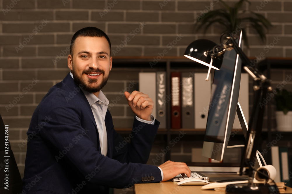 Poster smiling businessman working with computer in office at night