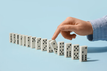 Naklejka premium Female hand with row of dominoes on color background, closeup