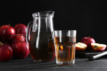 Tasty fresh apple juice and fruits on black wooden table