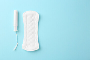 Menstrual pad and tampon on light blue background, top view. Space for text