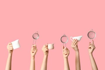 Female hands holding sieves with milk jugs on pink background