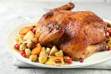 Delicious baked turkey, vegetables and cranberries on gray textured table, closeup