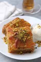 Tasty baklava with chopped nuts and scoop of ice cream on grey table, closeup