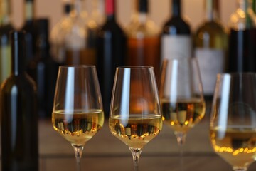 Tasty white wine in glasses against blurred background with festive lights, closeup. Bokeh effect