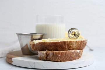 Slices of bread with butter, honey and milk on white table, closeup