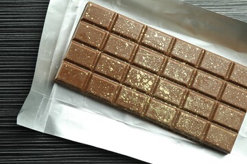 One tasty Dubai chocolate bar with pistachios and knafeh on black wooden table, top view