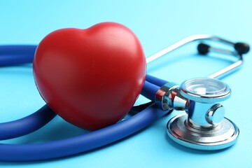 Cardiology. Stethoscope and red decorative heart on light blue background, closeup