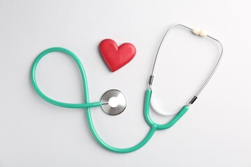 Cardiology. Stethoscope and red decorative heart on white background, flat lay