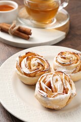 Freshly baked apple roses, honey, cinnamon sticks and tea on table, closeup